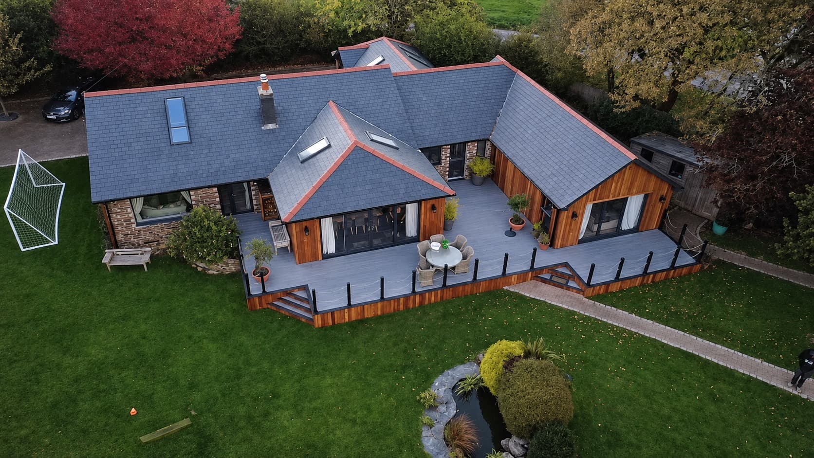 Aerial view of a completed slate roof on a large bungalow with decking in Cornwall by NL Roofing