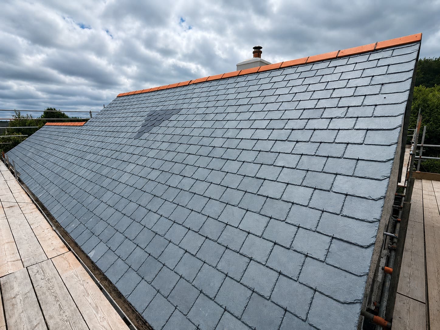 Close-up of freshly laid natural slate tiles with terracotta ridge on a new roof in Cornwall by NL Roofing